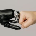 Een menselijke vuist geeft een boks aan een robotische hand als symbool voor samenwerking door automatisering.