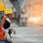 Bouwvakkers in werkkleding en helmen nemen pauze op de bouwplaats, passend bij het thema bouwpersoneel werven