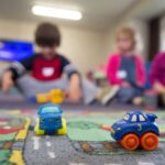 Kinderen spelen in een opvangruimte met speelgoedautootjes, passend bij opvang bij onregelmatige werktijden.