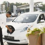 jongeman is zijn elektrische auto aan het opladen