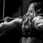 Vrouw tilt zware halter tijdens krachttraining, met focus op trainingsbelasting.