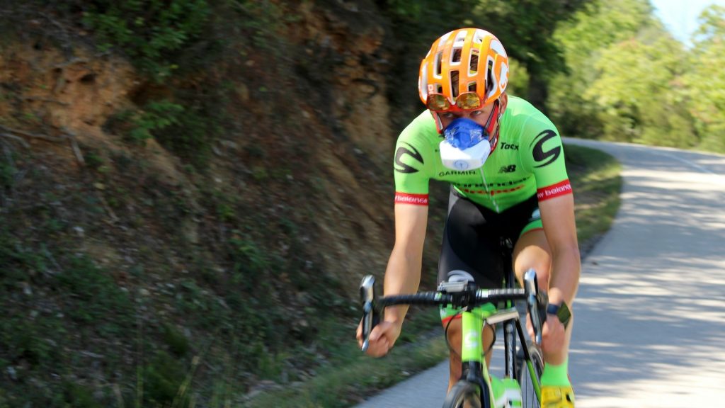 Wielrenner met trainingsmasker tijdens zuurstoftraining op een bergweg om ademhaling en uithoudingsvermogen te verbeteren