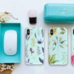 Verschillende gepersonaliseerde telefoonhoesjes met bloemenprints naast accessoires op een tafel