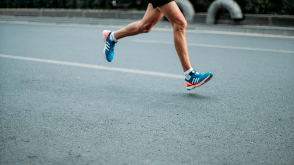 Hardloopschoenen tijdens een lange duurloop op een open weg bij zonsondergang