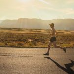 Hardloopschoenen tijdens een lange duurloop op een open weg bij zonsondergang