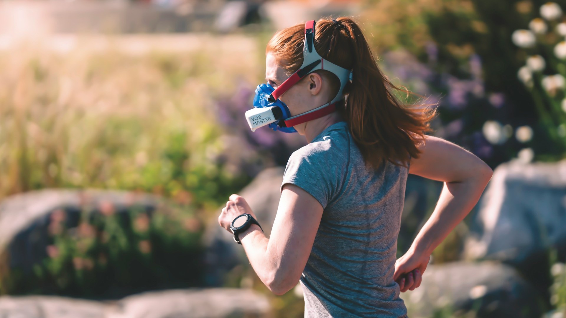 Hardloopster met trainingsmasker tijdens zuurstoftraining in de natuur om longcapaciteit en aerobe conditie te vergroten