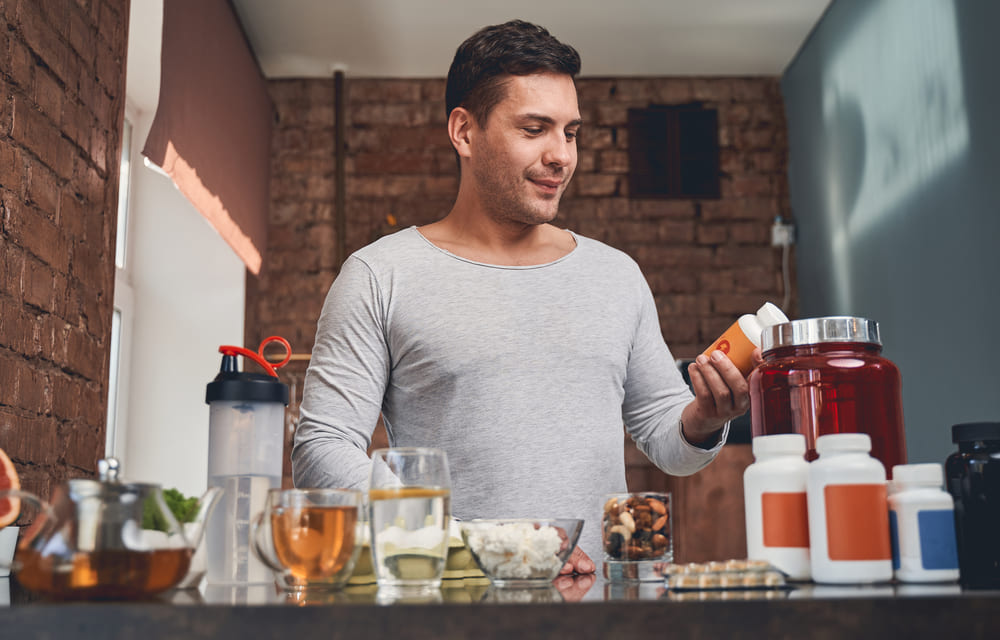 man vergelijkt supplementen in zijn keuken